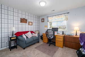 Office area featuring light carpet, an accent wall, visible vents, and wallpapered walls