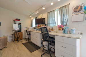 Home office with radiator heating unit, track lighting, and light wood finished floors