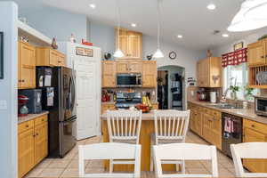 Kitchen featuring a sink, decorative backsplash, light tile patterned floors, lofted ceiling, and appliances with stainless steel finishes