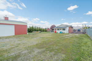 View of yard featuring an outdoor structure, fence, and a detached garage