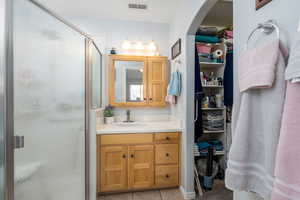 Bathroom with tile patterned floors, a stall shower, visible vents, a spacious closet, and vanity