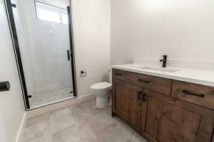 Bathroom featuring baseboards, a shower stall, toilet, and vanity