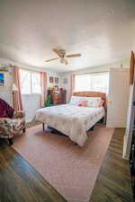 Bedroom with a textured ceiling, ceiling fan, and wood finished floors