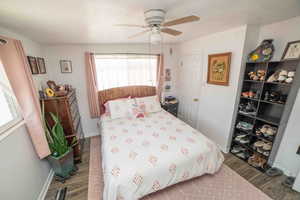 Bedroom with a ceiling fan, baseboards, and wood finished floors