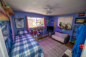 Bedroom featuring baseboards, a ceiling fan, a textured ceiling, and wood finished floors