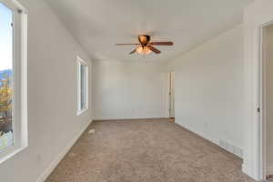 Unfurnished room featuring light carpet, visible vents, ceiling fan, and a healthy amount of sunlight