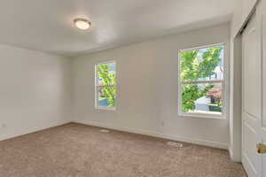Empty room featuring visible vents, light carpet, and baseboards