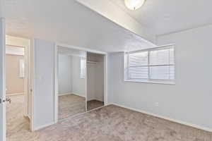 Unfurnished bedroom with baseboards, a closet, a textured ceiling, and carpet