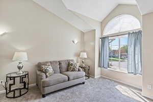 Living room featuring vaulted ceiling, carpet floors, baseboards, and visible vents
