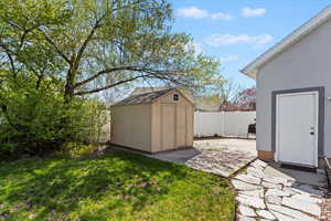 View of yard with a fenced backyard, a storage unit, an outdoor structure, and a patio