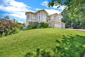 View of front facade with stucco siding, concrete driveway, a front lawn, and a garage