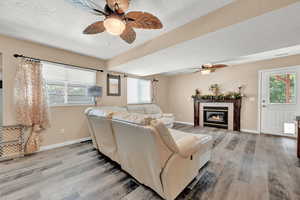 Living area featuring a ceiling fan, wood finished floors, a textured ceiling, and a healthy amount of sunlight