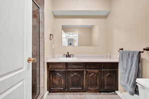 Bathroom with toilet, vanity, and a stall shower