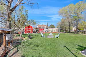View of yard featuring a shed, an outdoor fire pit, exterior structure, an outdoor structure, and fence
