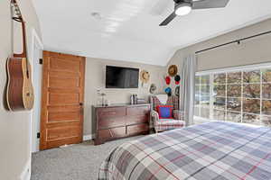 Carpeted bedroom featuring vaulted ceiling, baseboards, and a ceiling fan