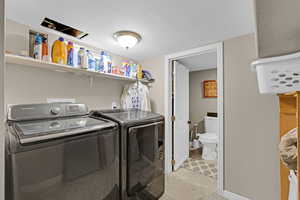 Laundry room featuring separate washer and dryer, a textured ceiling, and laundry area