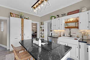 Kitchen with white cabinets, backsplash, a chandelier, and black electric cooktop