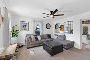 Living room with baseboards, a ceiling fan, and crown molding