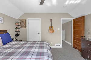 Carpeted bedroom with lofted ceiling, a ceiling fan, visible vents, and baseboards