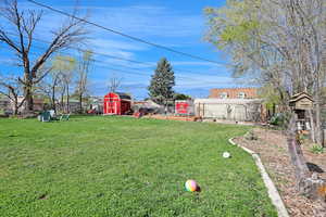 View of yard featuring an outdoor structure, fence, and a storage shed