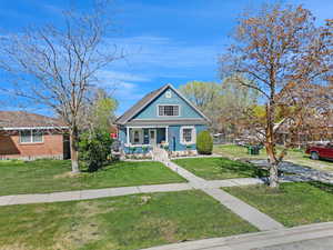 View of front of property featuring covered porch, a front lawn, and brick siding
