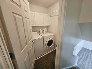 Clothes washing area featuring wood finished floors, independent washer and dryer, baseboards, cabinet space, and a textured ceiling