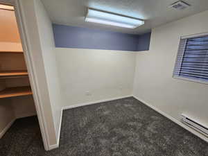 Smaller Bedroom to jack and Jill bath featuring baseboard heating, visible vents, and a textured ceiling