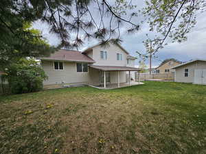 Back of property with an outdoor structure, a lawn, a patio, and fence