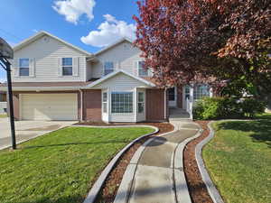 Townhome / multi-family property featuring a garage, driveway, a front lawn, and brick siding