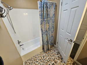 Full bath featuring shower / bath combo and baseboards