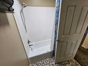 Full bath featuring a textured wall and shower / bathtub combination with curtain