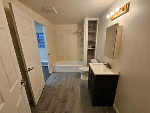 Jack and Jill Bathroom with lamanent floors, a textured ceiling, vanity,  shower combination, and toilet