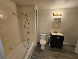 Jack and Jill Full bath with electric panel, a textured ceiling, toilet, vanity, and shower / tub combination