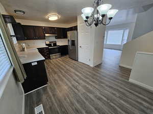 Kitchen featuring stainless steel appliances, a sink, a chandelier, light countertops, and under cabinet range hood