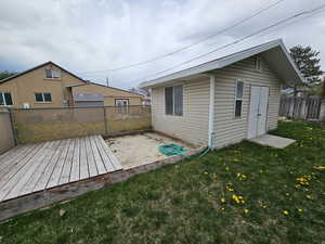Exterior space featuring a wooden deck, a fenced backyard, an outbuilding, and a yard
