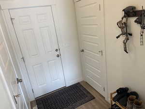 Doorway to outside with dark wood-type flooring and baseboards