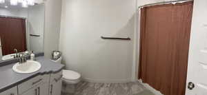 Full bathroom with marble finish floor, toilet, and vanity