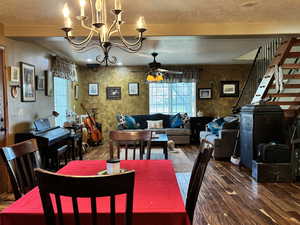 Dining space and living room with hardwood / wood-style floors, a textured ceiling, and ceiling fan with notable chandelier