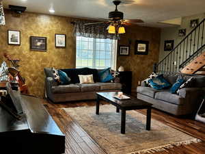 Living room featuring hardwood / wood-style floors, a textured ceiling, stairs, and ceiling fan