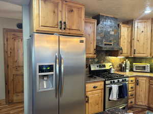 Kitchen featuring stainless steel appliances, a toaster, a textured ceiling, dark wood-style flooring, and decorative backsplash