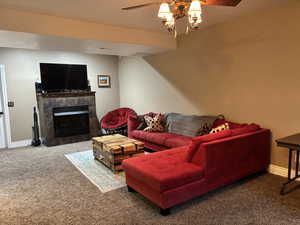 Carpeted family room with a ceiling fan, baseboards, and a tile fireplace