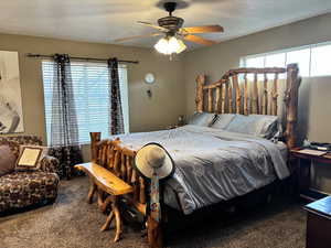 Primary bedroom on main floor with a ceiling fan, carpet flooring, and a textured ceiling
