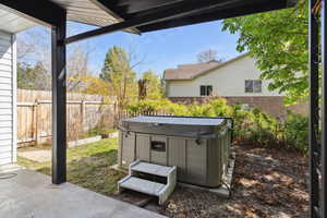 View of yard featuring a hot tub, a patio, and fence