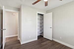 Unfurnished bedroom with dark wood-type flooring, a closet, and baseboards