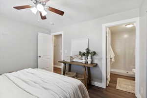 Bedroom featuring ensuite bath, baseboards, a ceiling fan, and dark wood-style floors