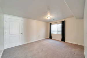 Empty room with light colored carpet and baseboards