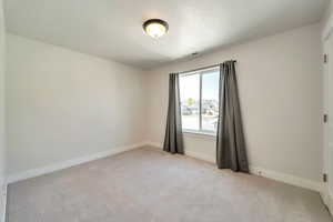 Unfurnished room with light carpet, visible vents, and baseboards