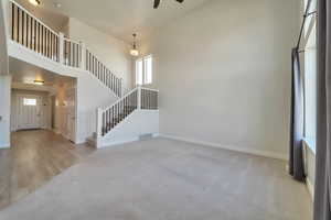 Unfurnished living room featuring stairway, a ceiling fan, visible vents, and plenty of natural light