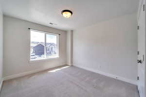 Unfurnished room featuring visible vents, baseboards, and light carpet