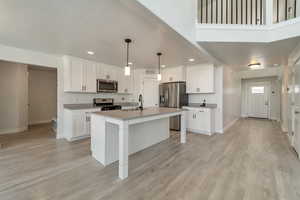 Kitchen with recessed lighting, white cabinetry, baseboards, and stainless steel appliances
